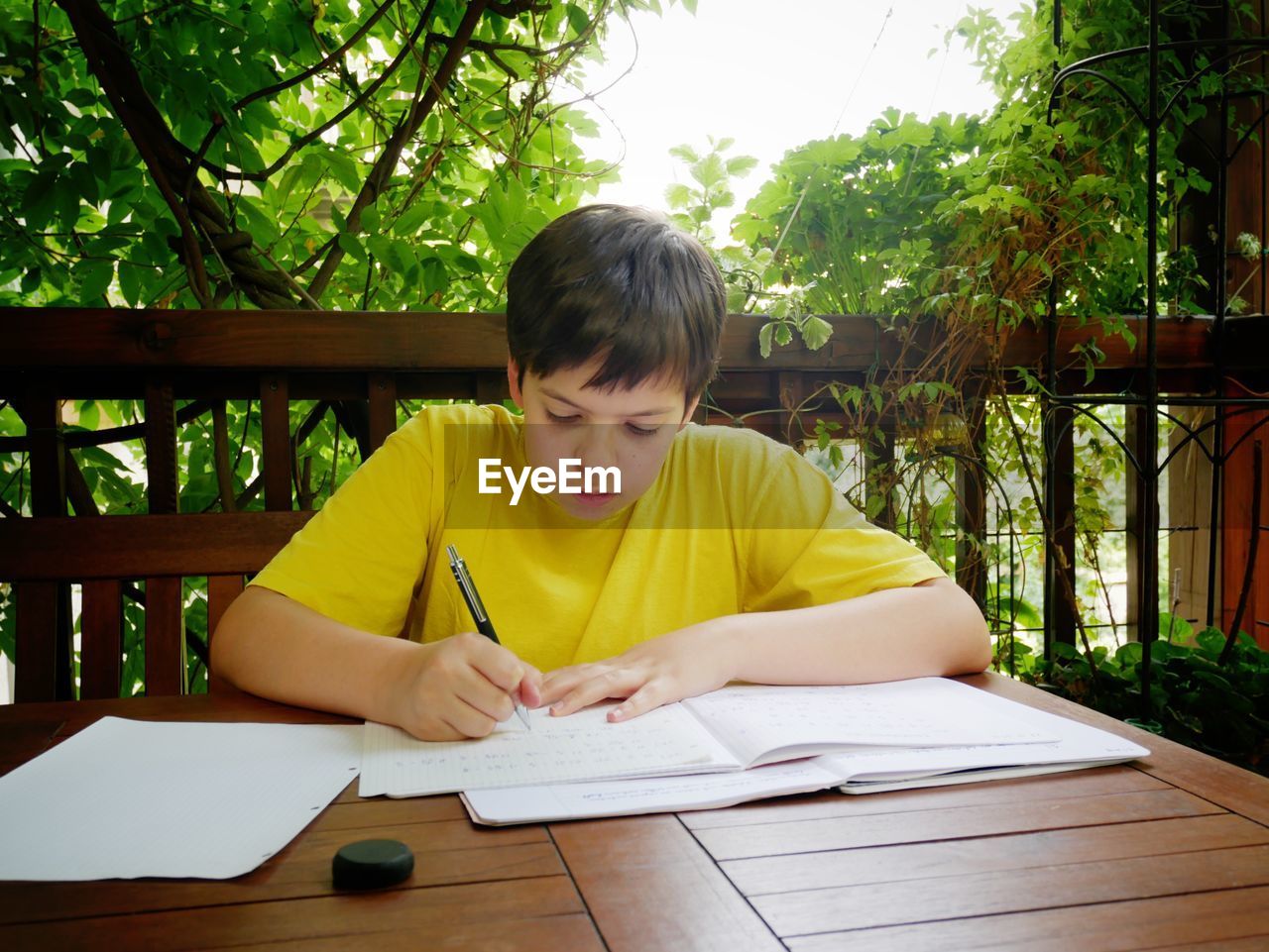 Boy studying at table in porch