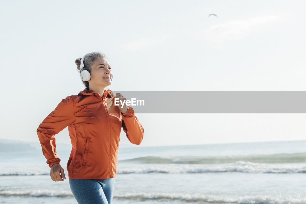 Smiling mature woman jogging on beach