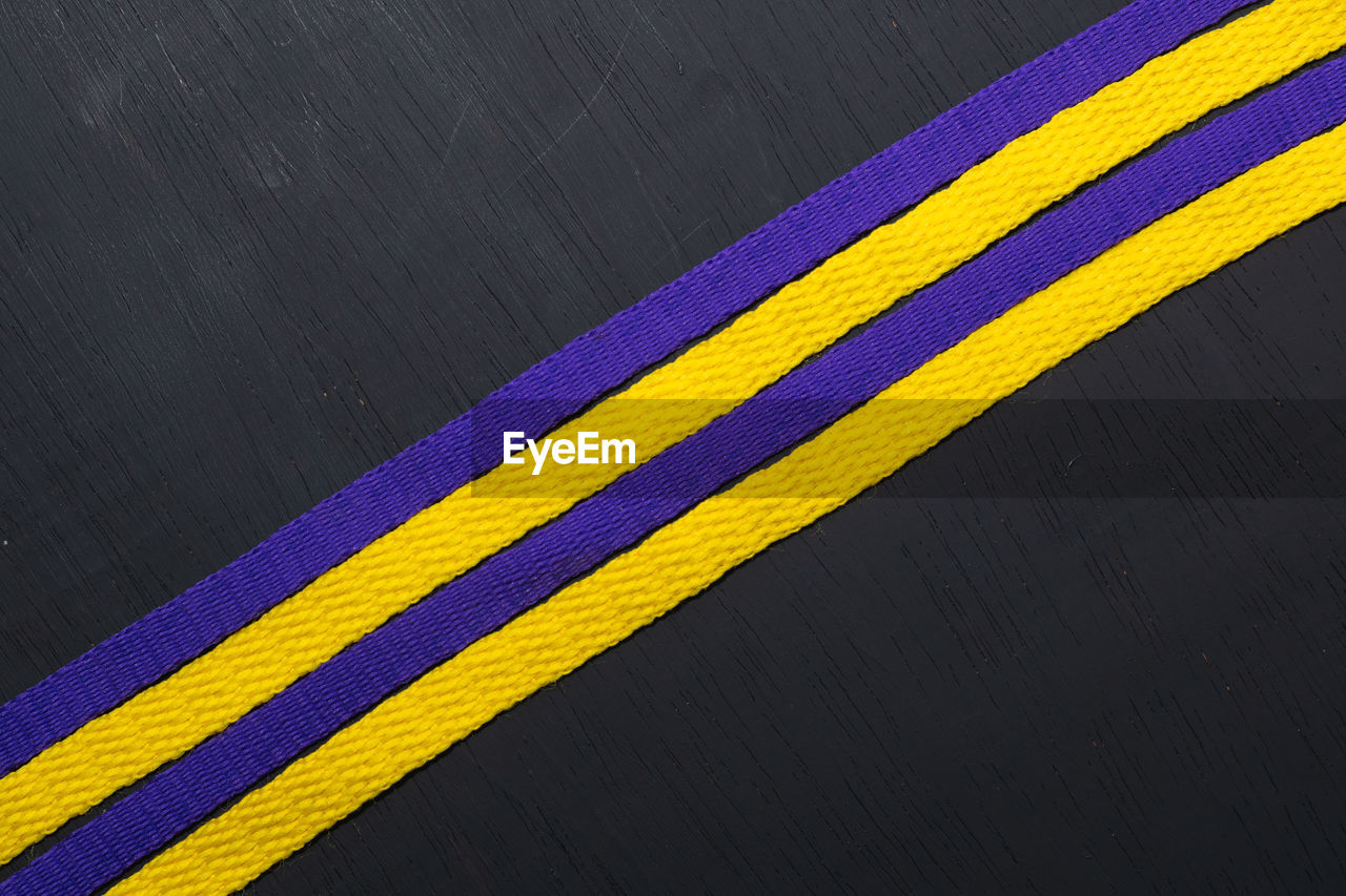 Yellow and purple shoelaces, lakers flag, on black wooden background