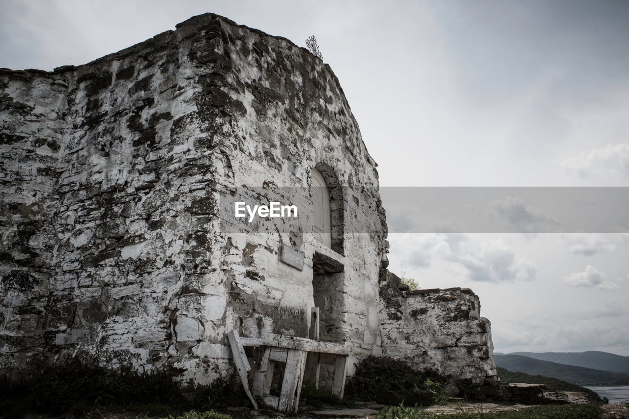 LOW ANGLE VIEW OF OLD RUIN BY MOUNTAIN AGAINST SKY