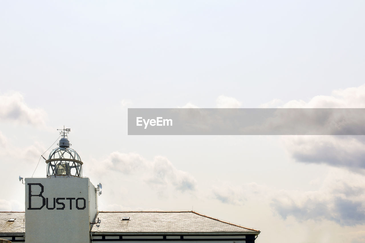 HIGH SECTION OF TEXT ON BUILDING ROOF AGAINST SKY