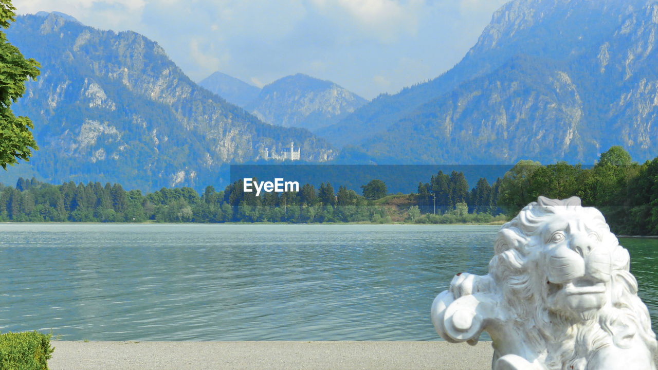 STATUE AGAINST LAKE AND MOUNTAINS