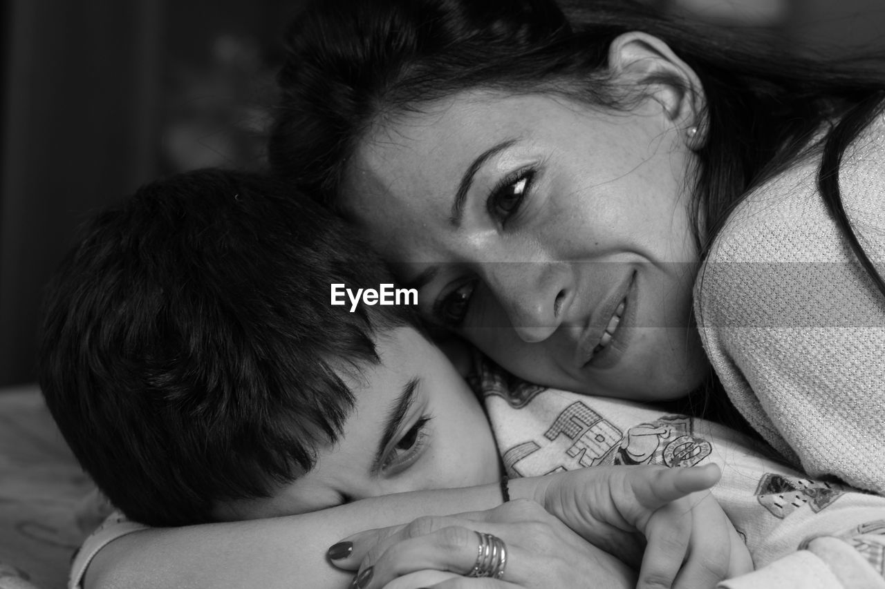 Close-up of mother with son lying on bed