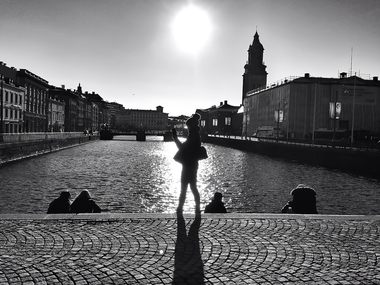 Silhouette woman standing at canal during sunset