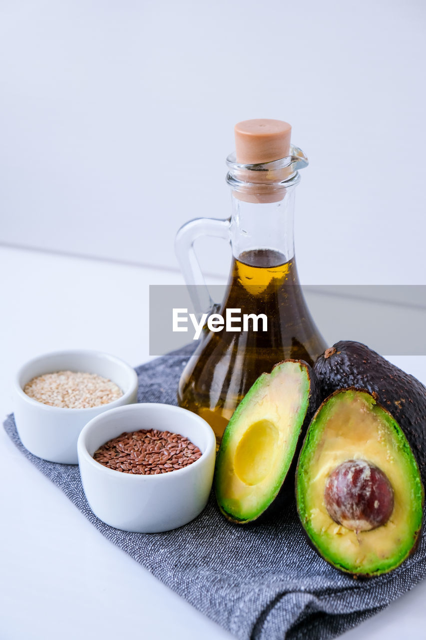 Olive oil in glass bottle with sesame and flax seeds. fresh ripe hass avocado. 