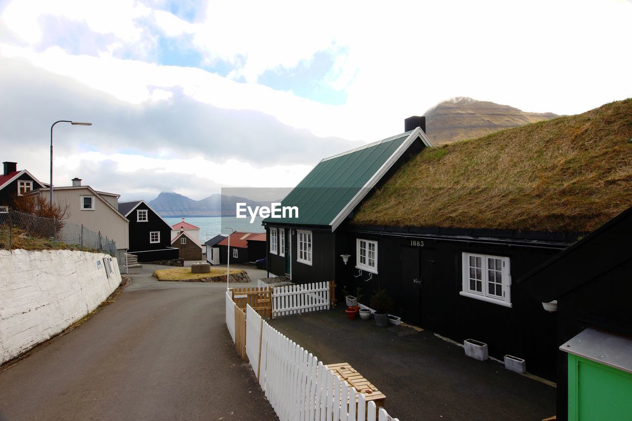 ROAD AMIDST HOUSES AND BUILDINGS IN CITY