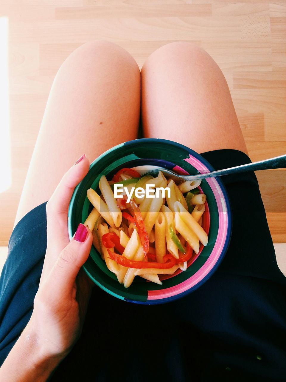 Low section of woman with pasta on lap at home