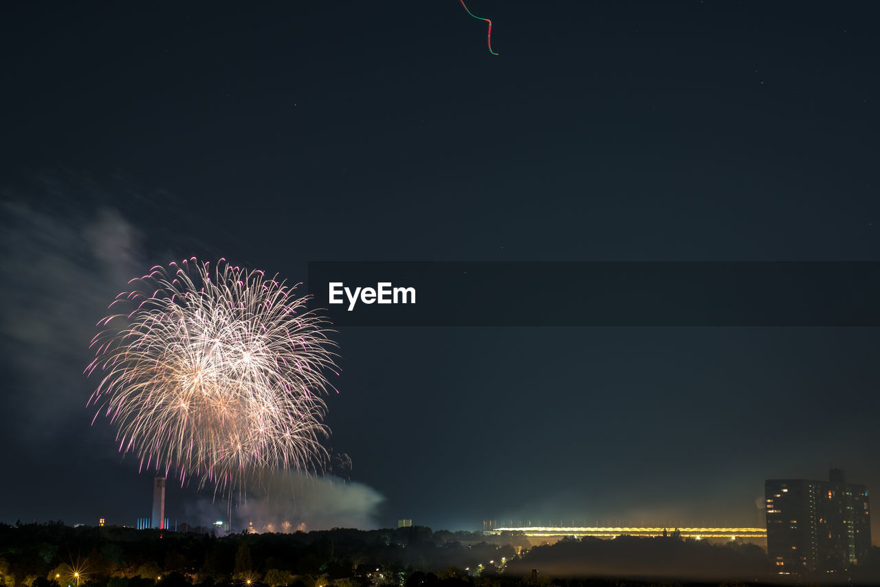 FIREWORK DISPLAY OVER CITY AGAINST SKY AT NIGHT