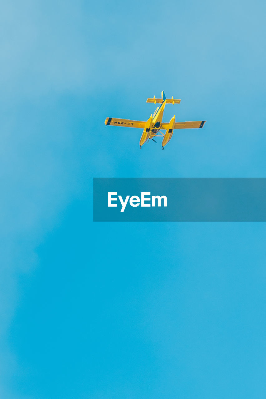 Low angle view of airplane flying against clear blue sky