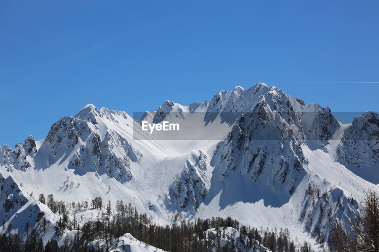 Wide panormaric view of moutains with white snow in winter from lussari mount in northern italy