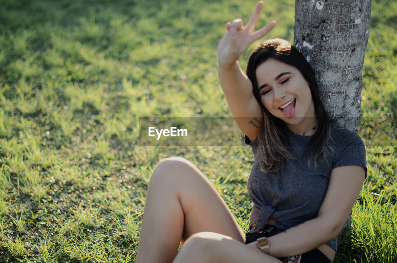 Beautiful young woman sitting on field