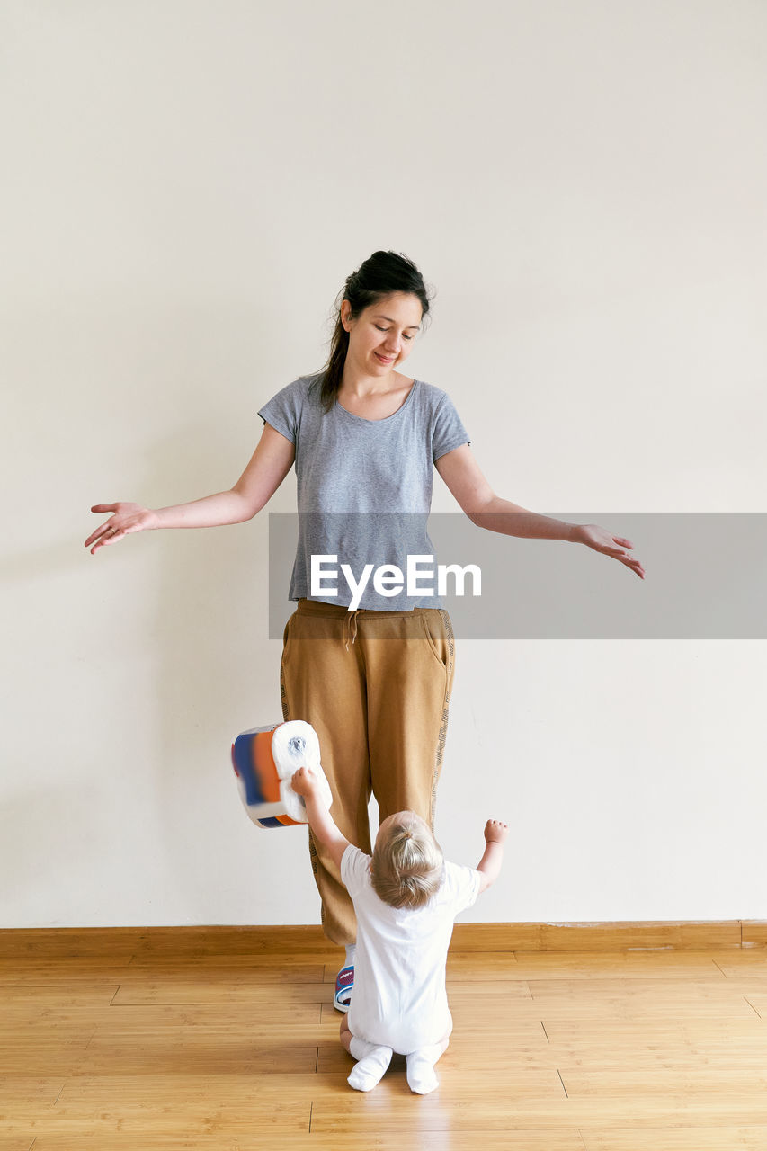 Full length of mother and baby girl on floor at home