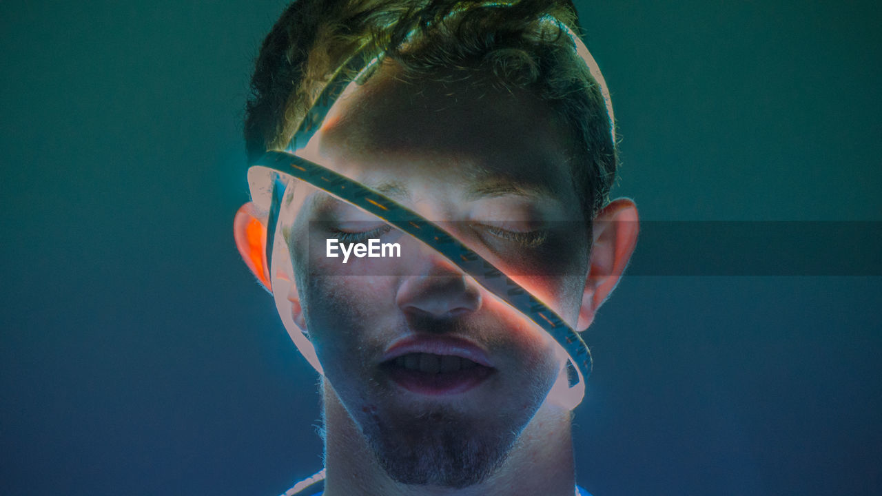 Man with illuminated lighting equipment wrapped on face against colored background