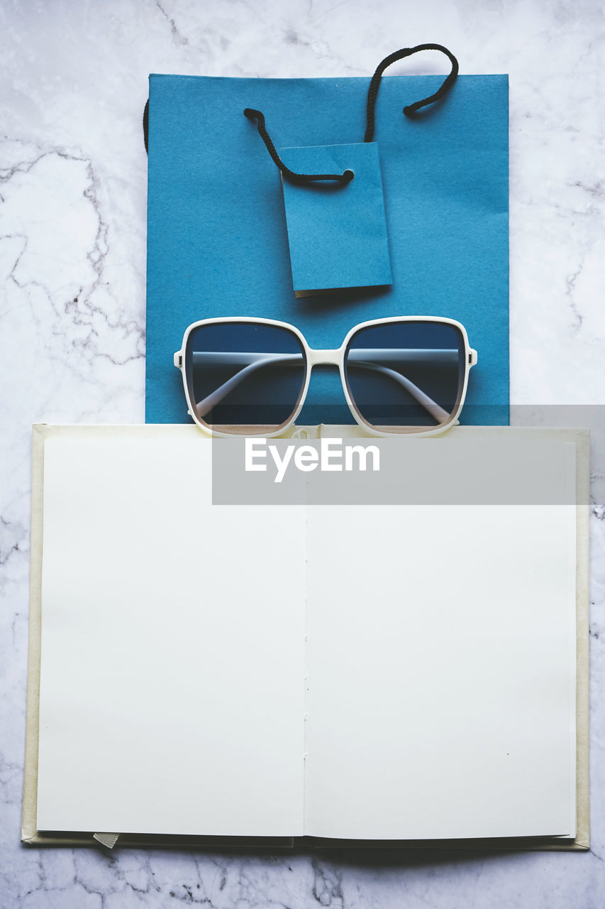 glasses, eyeglasses, blue, indoors, fashion, no people, copy space, still life, sunglasses, paper, studio shot, table, turquoise, publication, directly above, communication