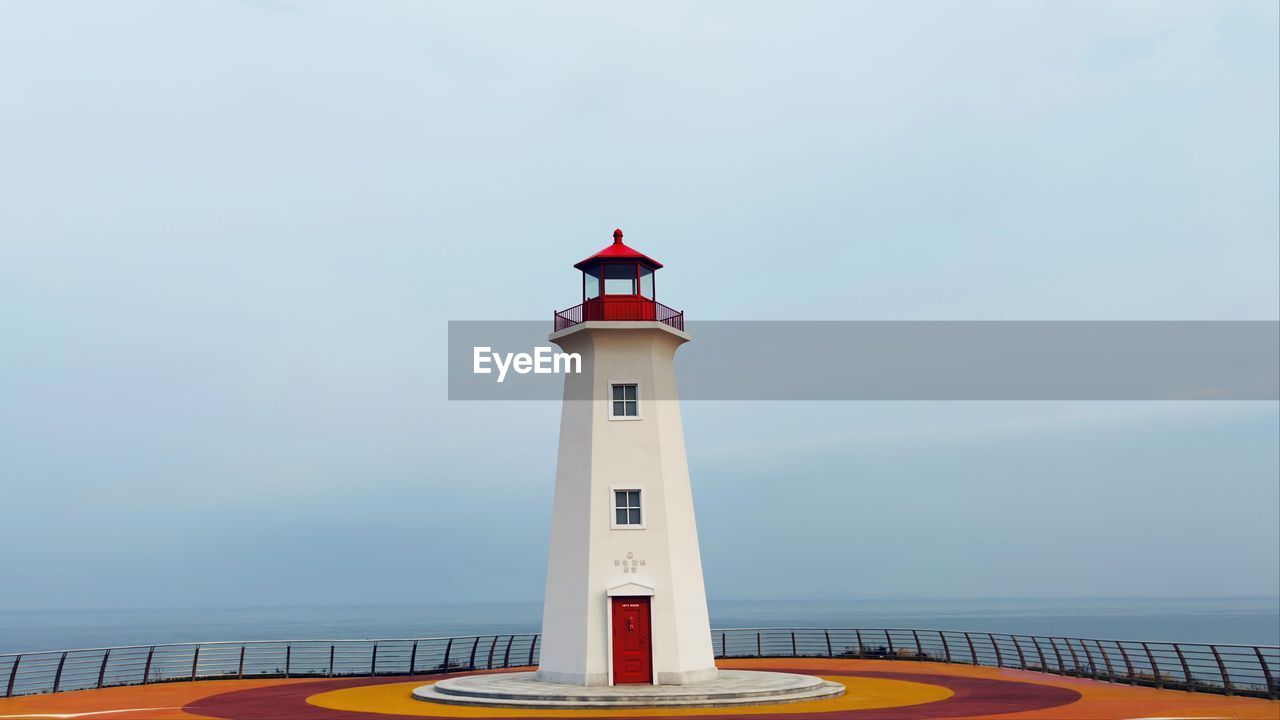 Lighthouse by sea against sky