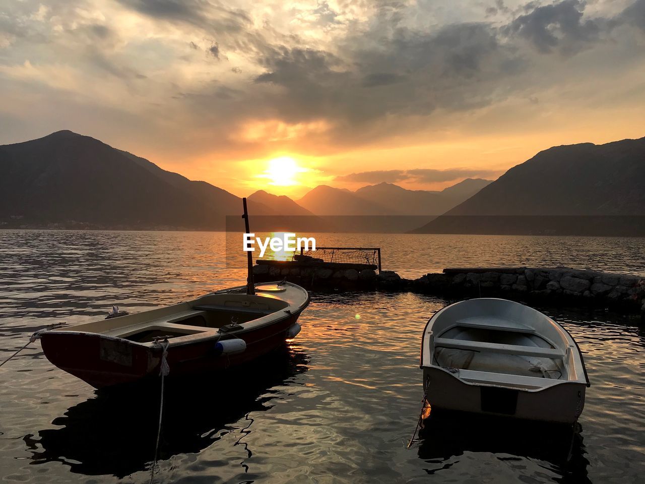 BOAT MOORED IN SEA AGAINST SKY DURING SUNSET