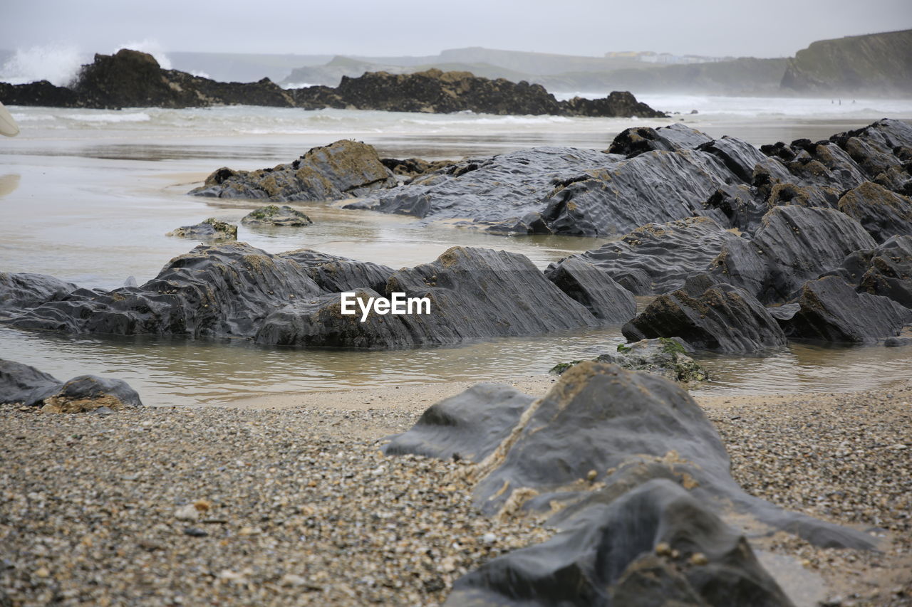 Scenic view of rocks on beach against sky