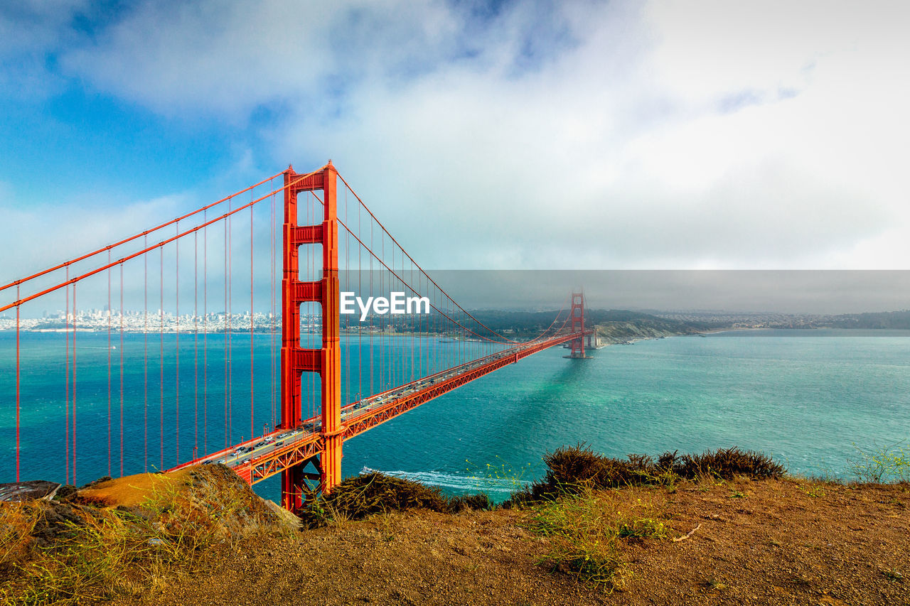 Golden gate bridge over sea against cloudy sky