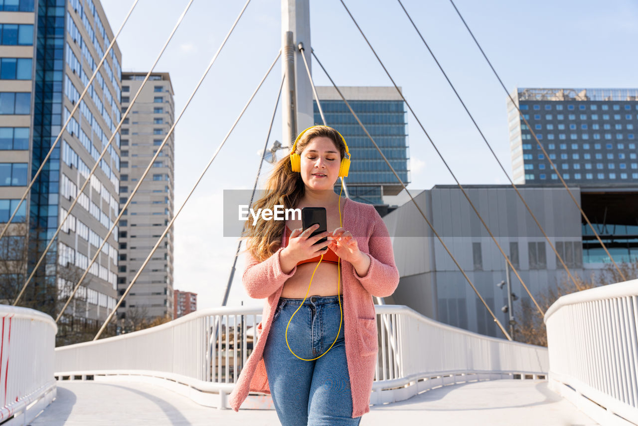 Full length of woman using mobile phone on bridge