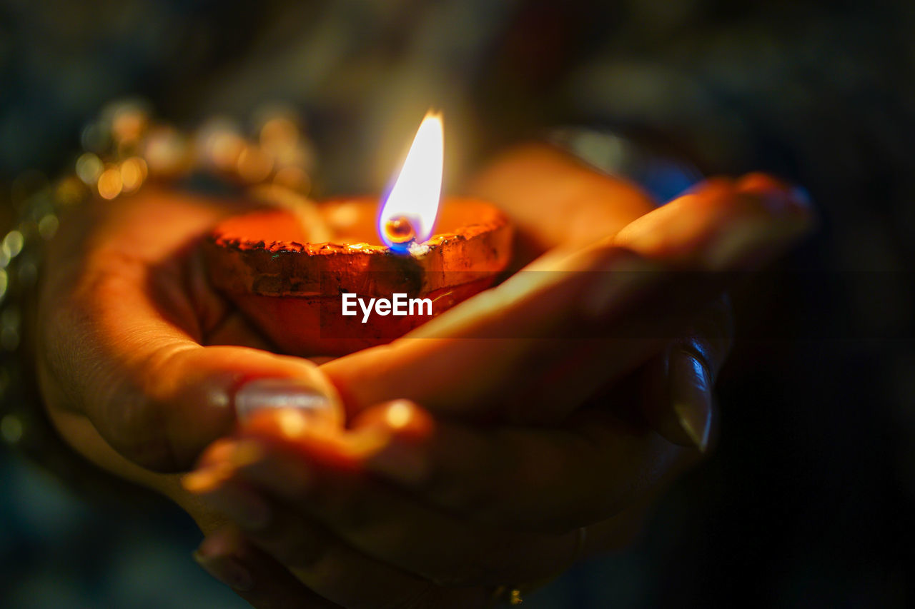 Close-up of hand holding lit candles