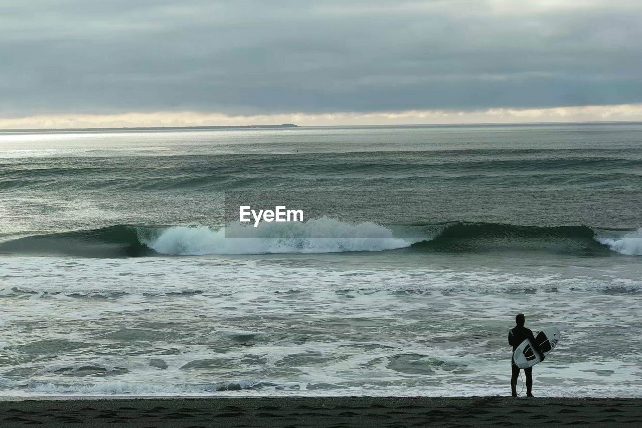 MAN SURFING ON SEA AGAINST SKY