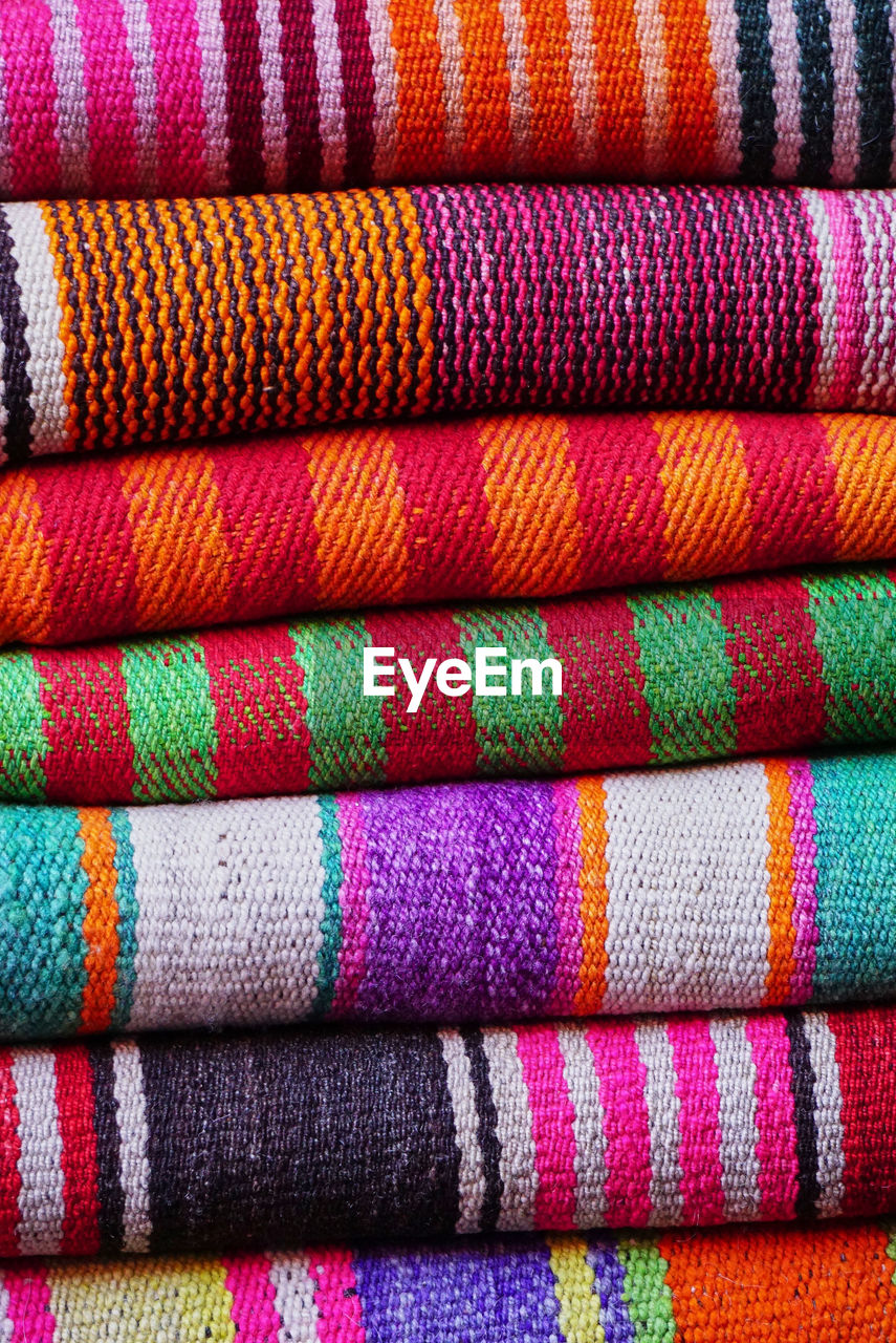 A heap of multi coloured traditional peruvian woven textiles at a street market, peru