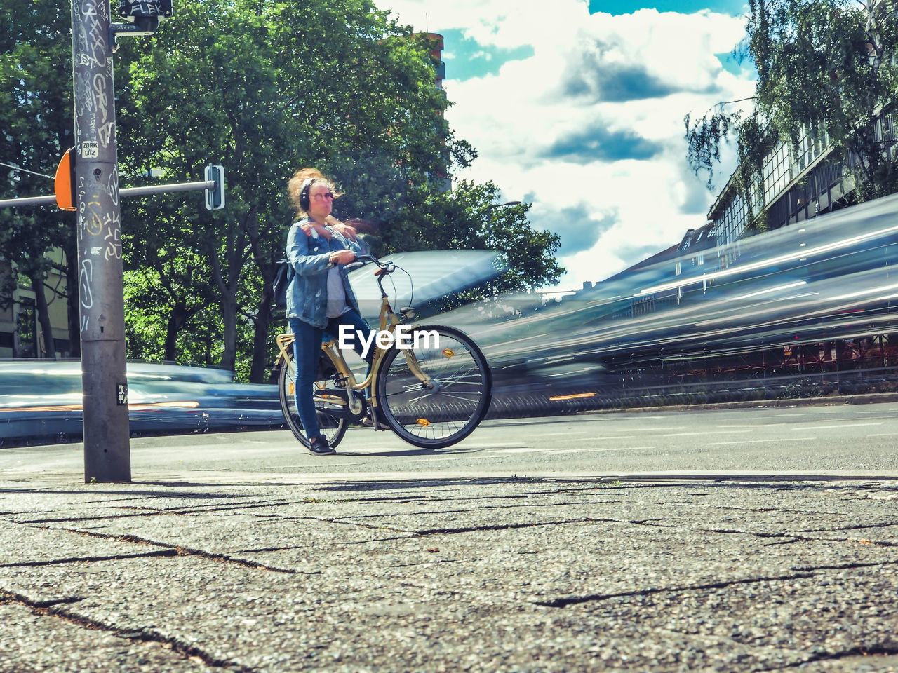 MAN RIDING BICYCLE ON ROAD AMIDST TREES IN CITY