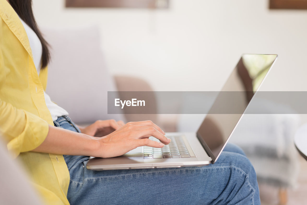 midsection of woman using laptop while sitting on table