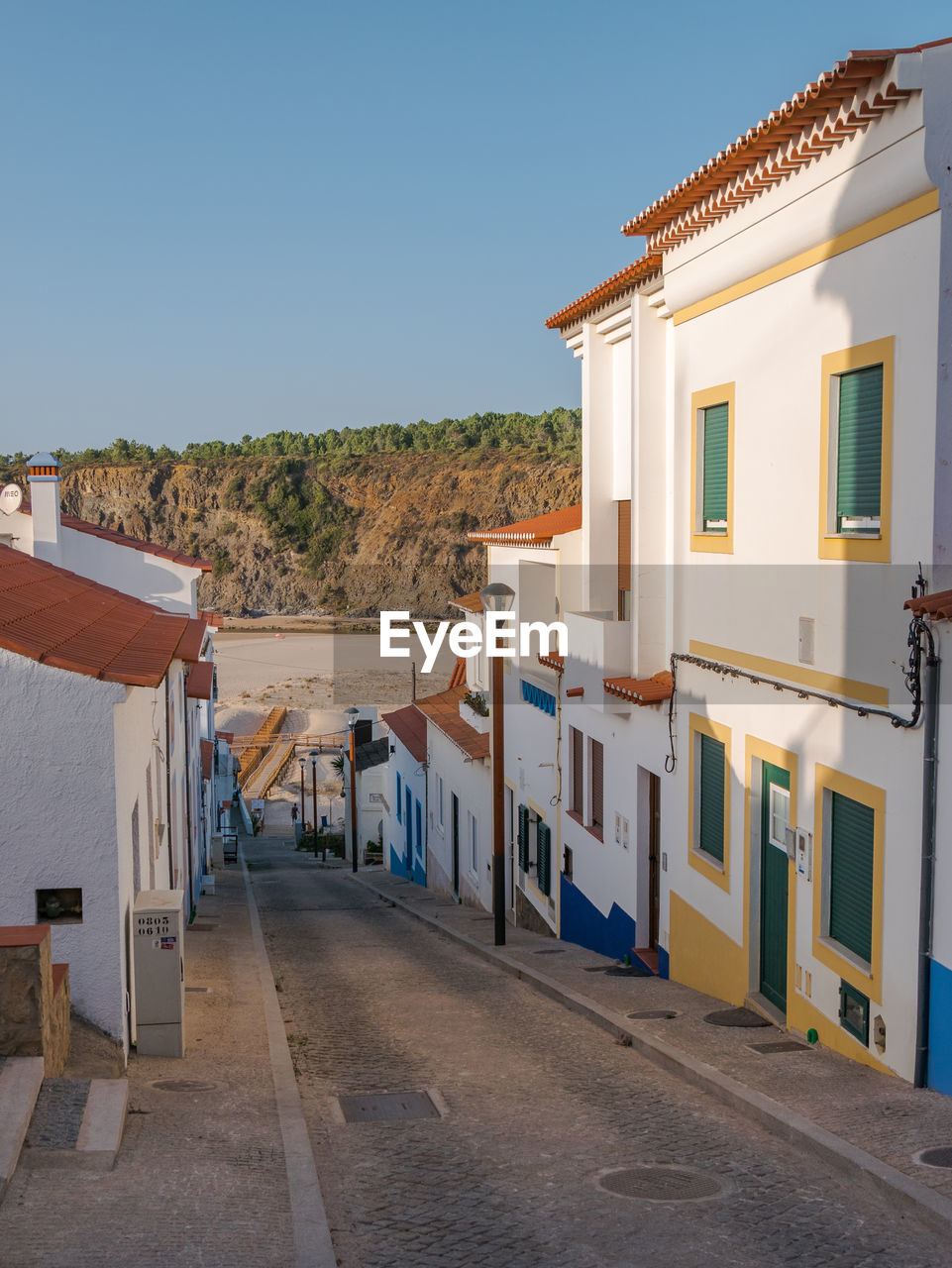 Houses by street in city against clear blue sky