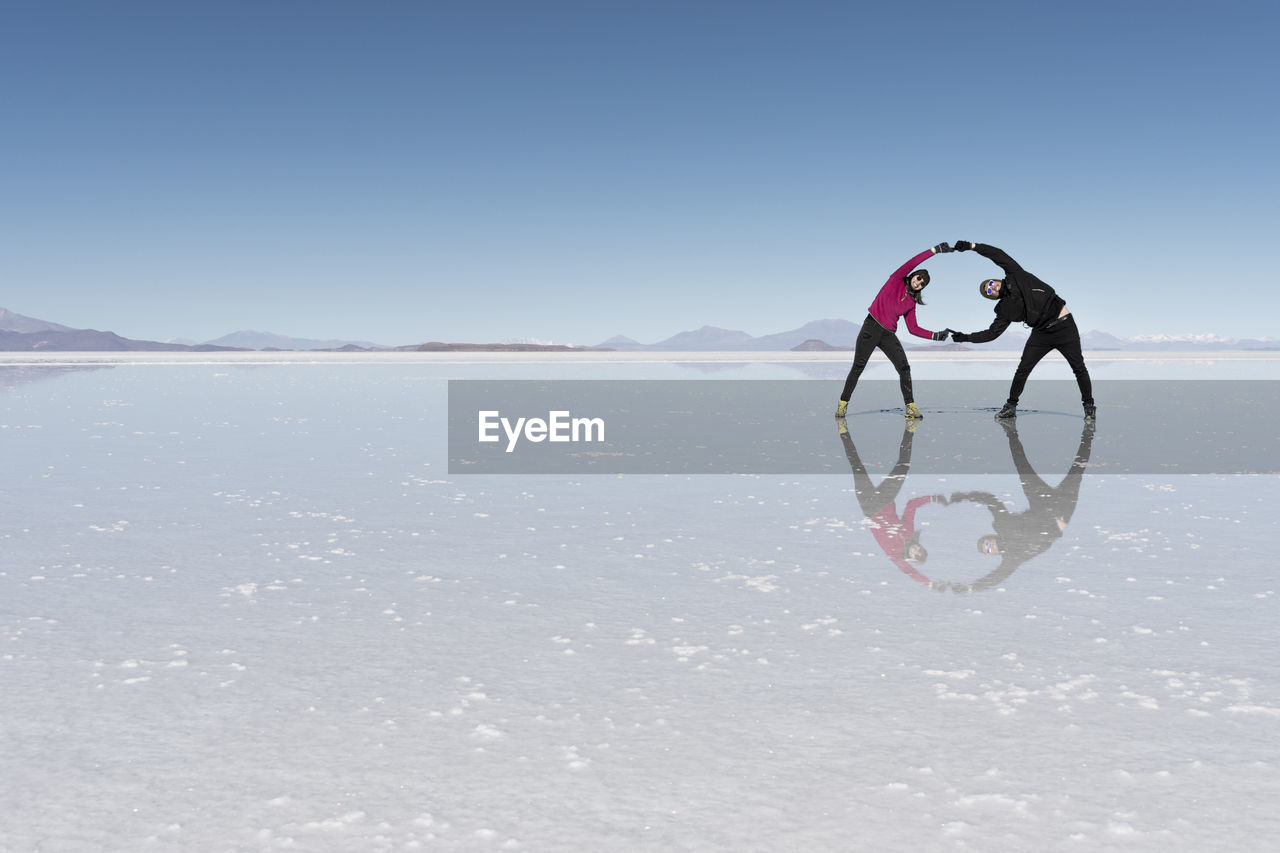 Couple holding hands while standing on salt flat