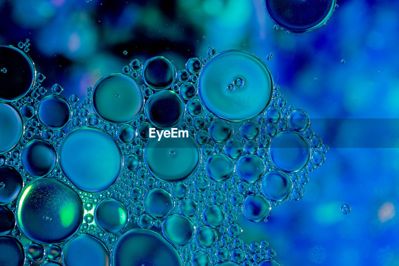 CLOSE-UP OF WATER DROPS ON BLUE GLASS