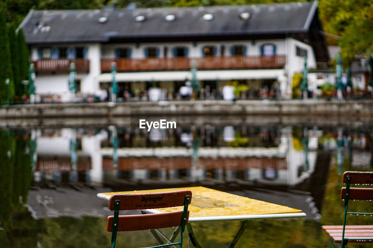 Wooden table by canal against building