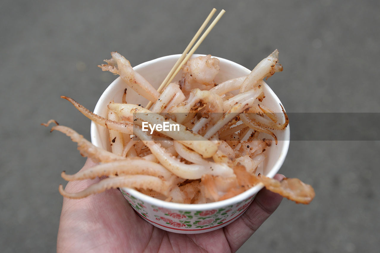 Cropped hand holding fried cuttlefish in bowl