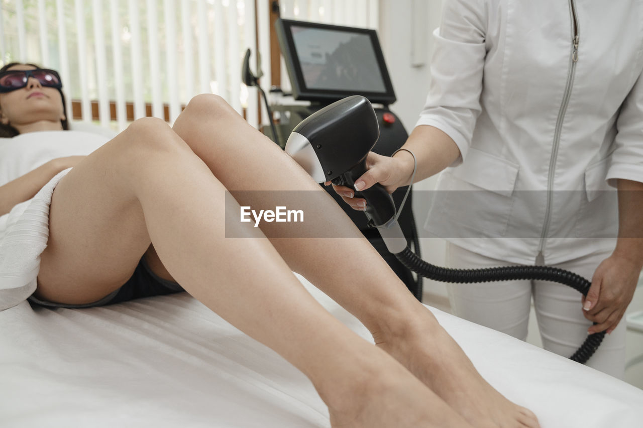 Aesthetician removing hair on woman's legs with laser