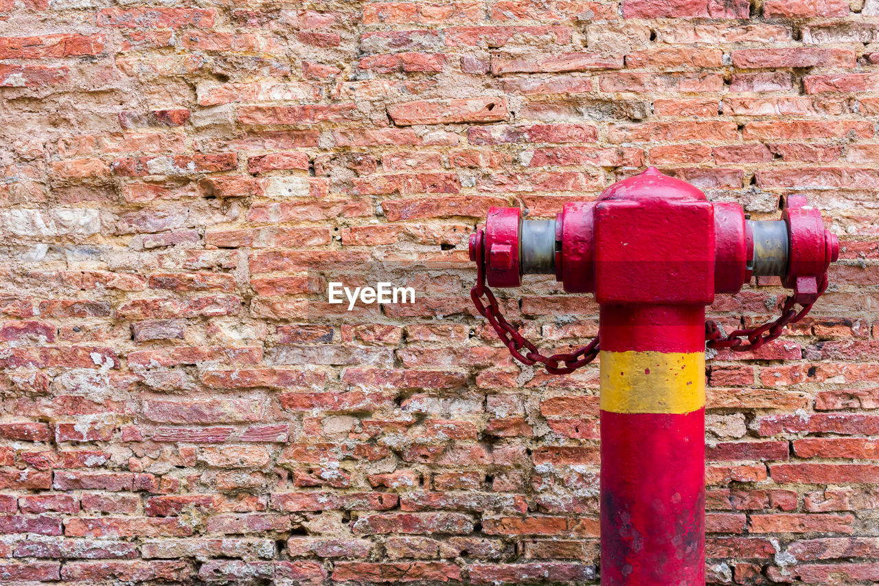 Close-up of fire hydrant against brick wall