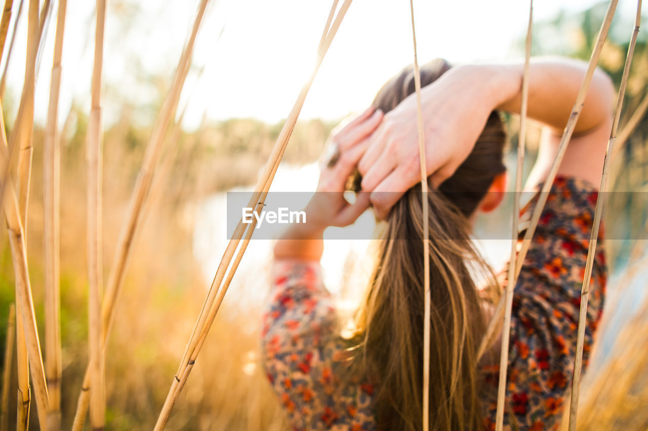 Woman tying hair against plants