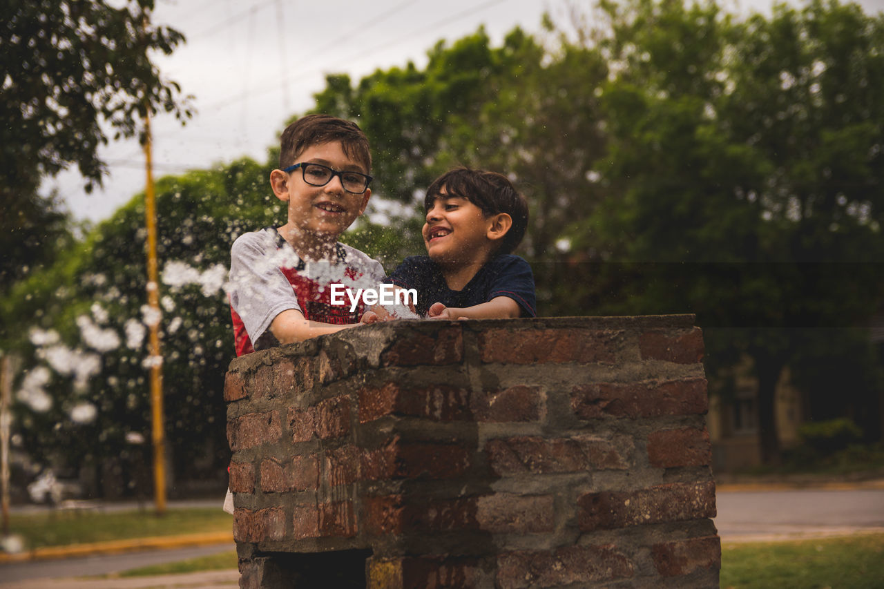 Boys playing with water in drinking fountain outdoors