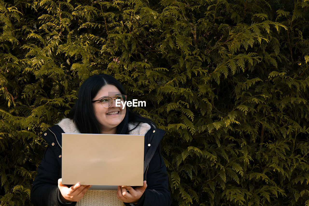 Young woman holding laptop. social media work. woman in the park.