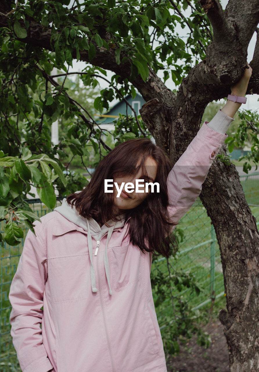 WOMAN STANDING BY TREE