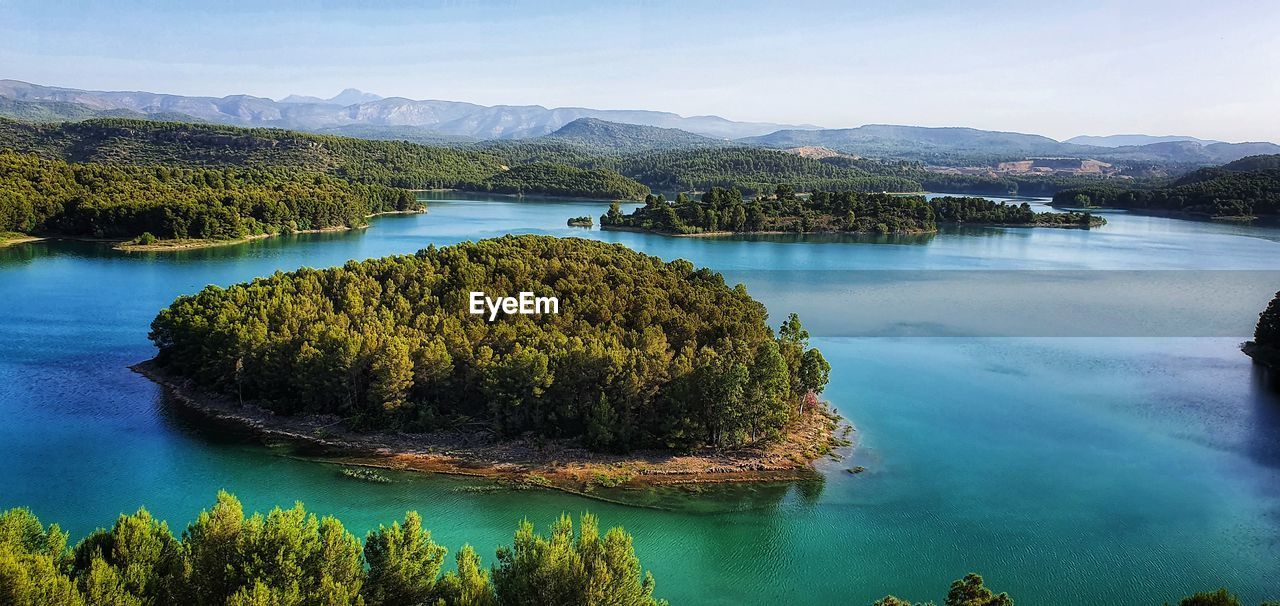 water, scenics - nature, beauty in nature, reflection, body of water, mountain, lake, tree, environment, nature, sky, tranquility, land, reservoir, plant, landscape, tranquil scene, travel, travel destinations, no people, forest, crater lake, blue, idyllic, outdoors, tourism, mountain range, day, high angle view, non-urban scene, pinaceae, vacation, pine tree, trip, coniferous tree, holiday, cloud, nautical vessel, beach, lagoon