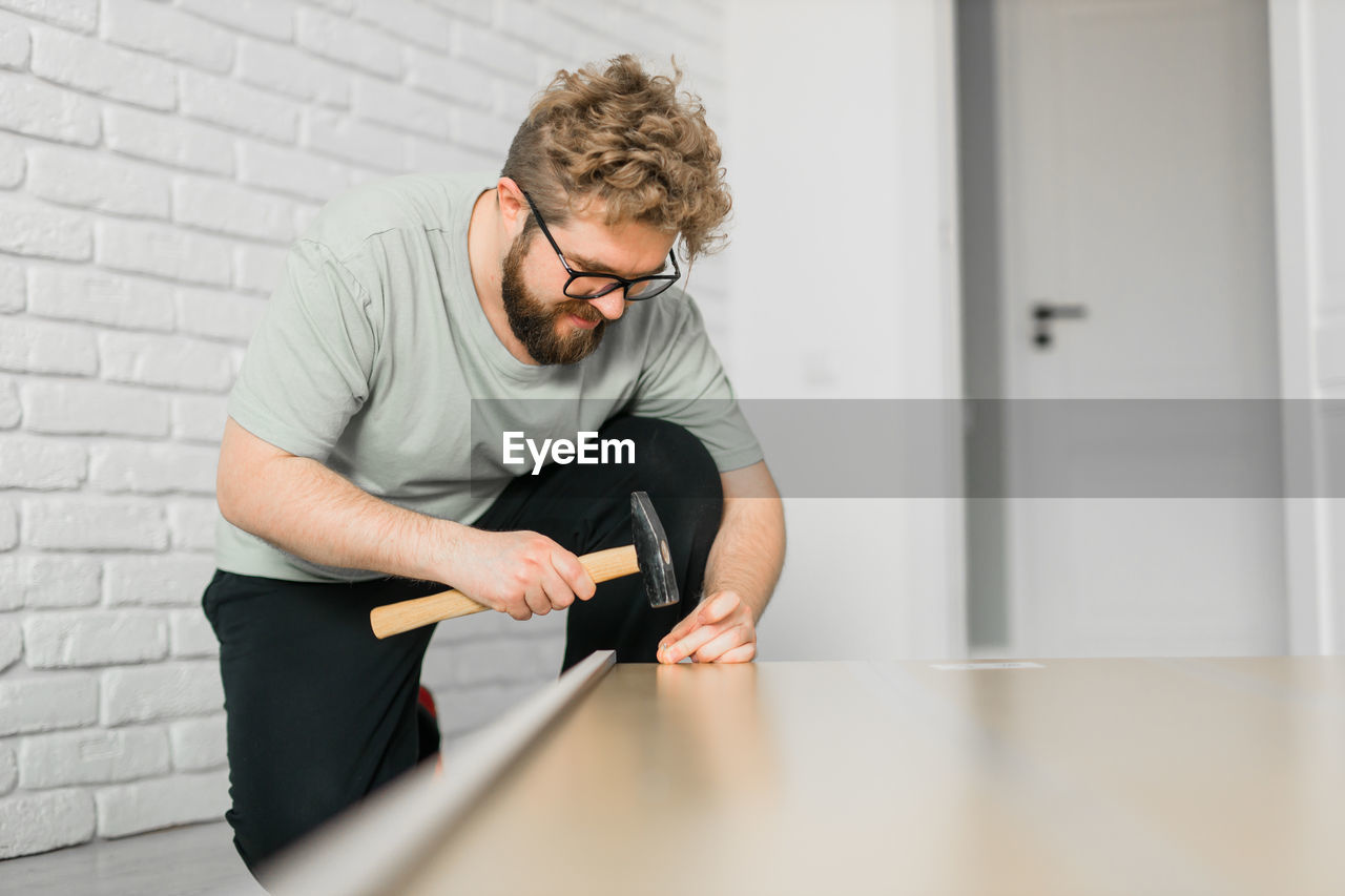 side view of young man using mobile phone while sitting on table