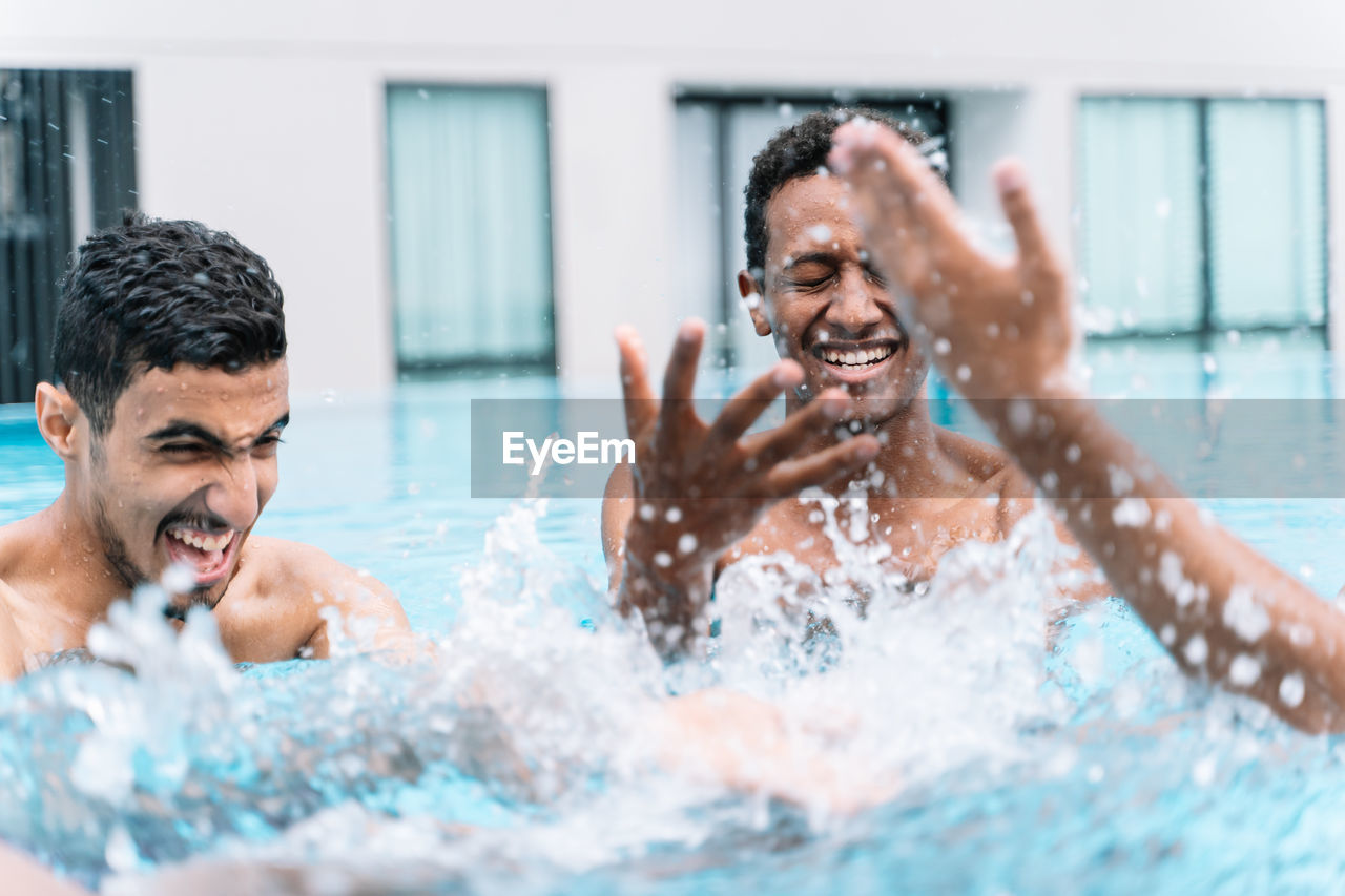 Man smiling as he plays in a circle with a group of friends in a pool