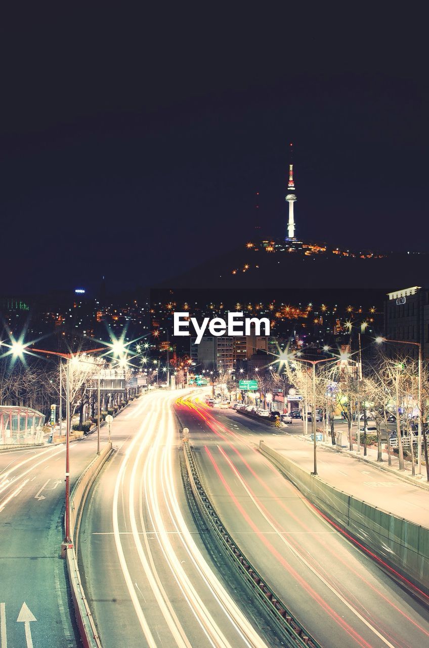 Light trails on road at city with n seoul tower in background at night