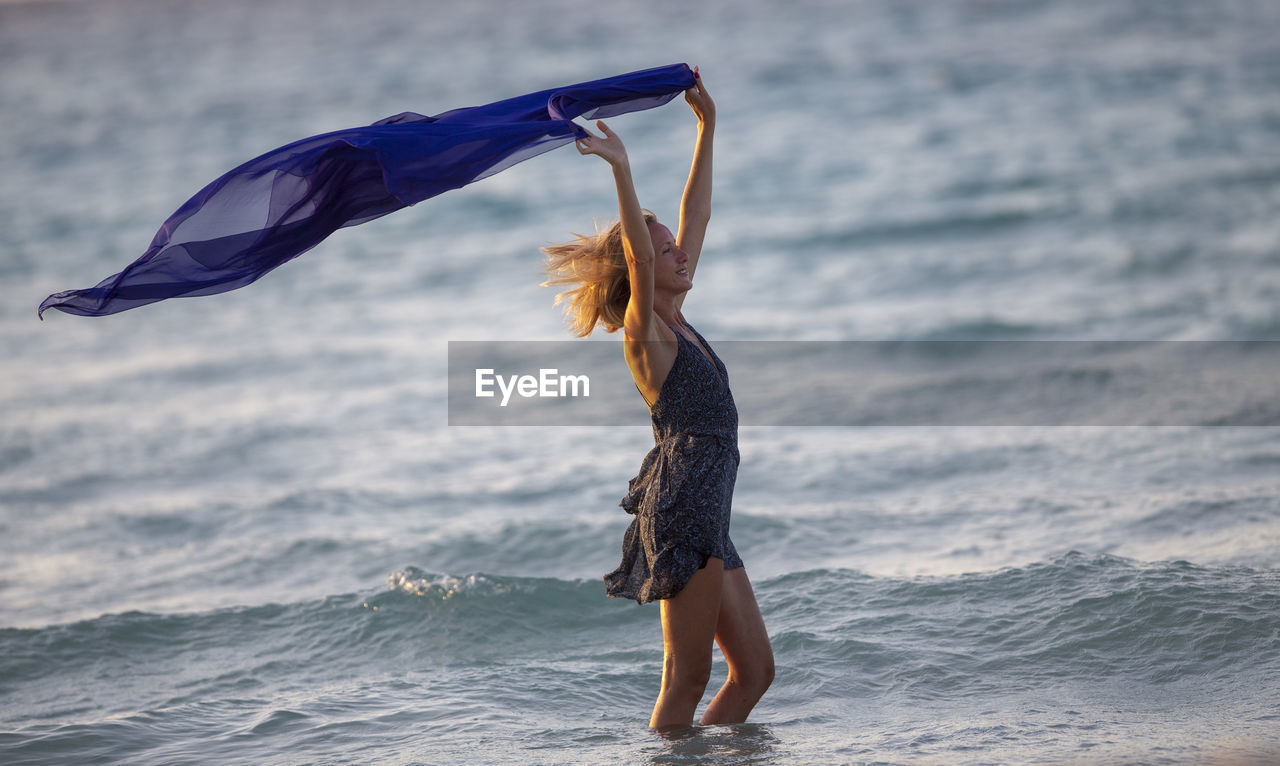 water, sea, one person, nature, beach, women, motion, adult, land, sports, clothing, full length, young adult, wave, leisure activity, holiday, hairstyle, vacation, lifestyles, trip, long hair, surfing, outdoors, day, carefree, beauty in nature, enjoyment, side view, wind, female, arm, happiness, limb, ocean, fun, vitality, environment, sky, emotion, summer, standing, child
