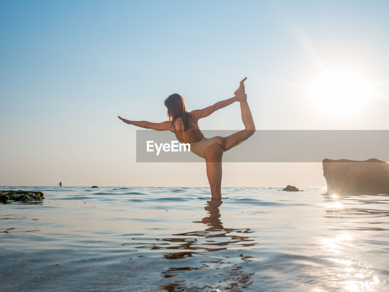 Woman doing yoga in sea against sky