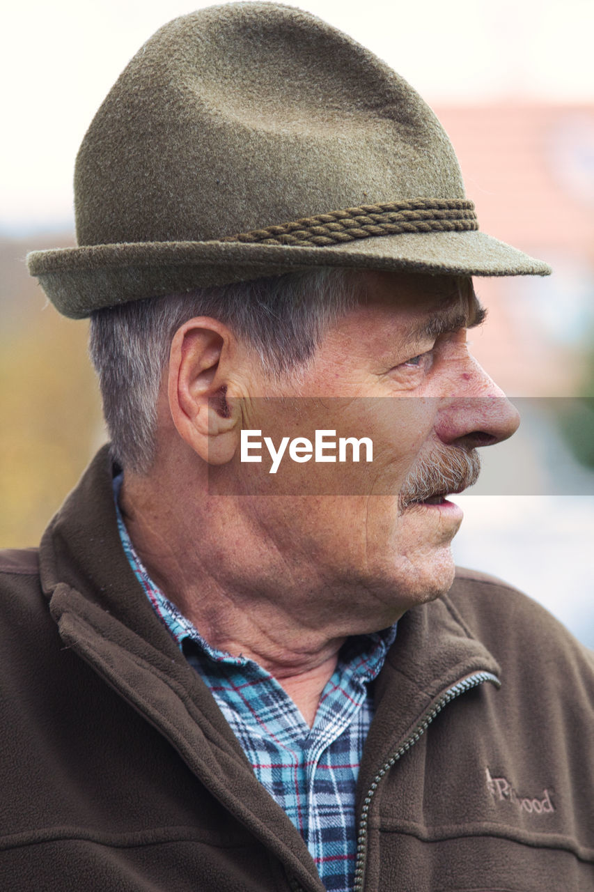 PORTRAIT OF MAN WEARING HAT LOOKING AWAY OUTDOORS