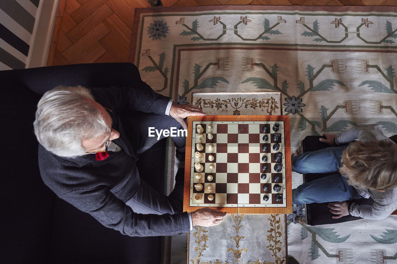 Grandfather and grandson playing chess in living room