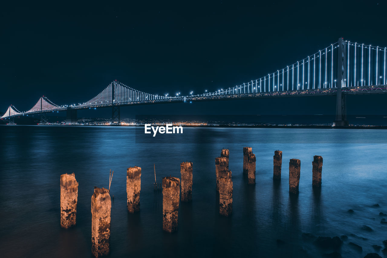 View of bridge over calm sea at night