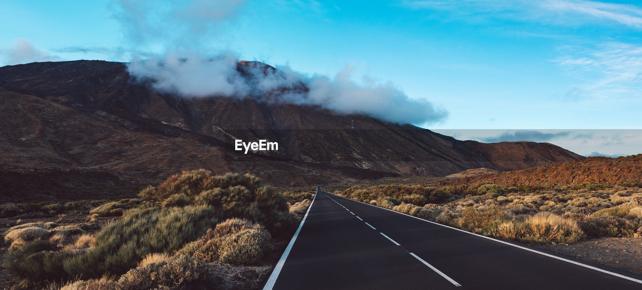 Road leading towards mountains against sky