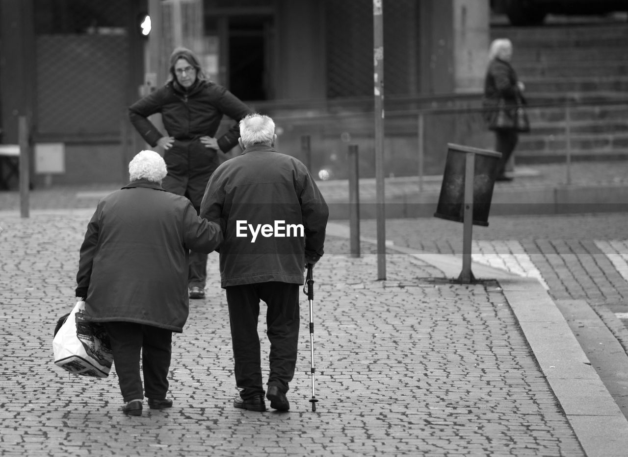 Woman looking at couple on road in city